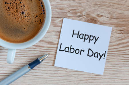 Happy labor day message on wooden table background with morning coffee mug labour day celebrated at may 1 spring time