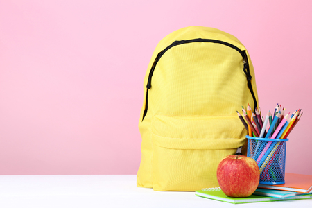 Yellow backpack with school supplies on pink background Stock Photo