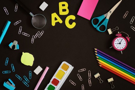 In tsetre black background blank space for text mock up bright colored school and office supplies are arranged around Stock Photo