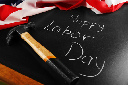 Happy labor day text and hammer on blackboard