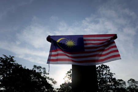 Independence day concept a happy and proud citizen holding malaysian flag sky background Stock Photo