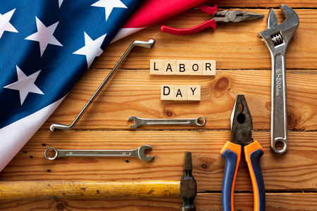 Usa labor day concept first monday in september different kinds on wrenches handy tools america flag and wooden blocks on wooden table Stock Photo