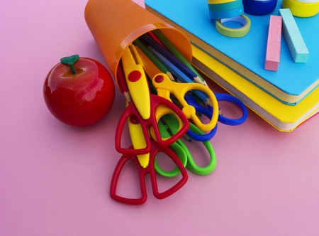 The schoolboy s accessories lie on a pink table textbooks and office back to school