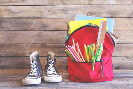 Backpack with school supplies on wooden table