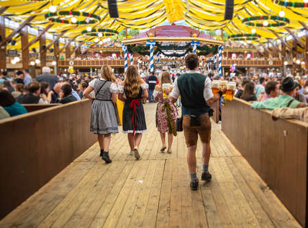 Oktoberfest munich germany waiter with traditional costume holding beers crowded tent interior background Stock Photo