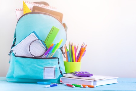 Full turquoise school backpack with stationery on table concept back to school