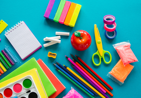 Stationery for study at school lies on blue back to school books and textbook apple material for creativity view from above rainbow color