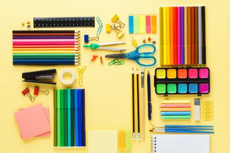 Set of various colorful school stationery and supplies on yellow background geometrically aligned flat lay copy space