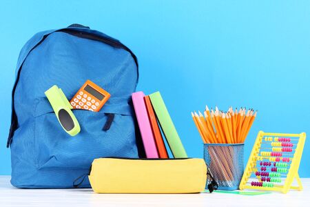 Backpack with school supplies on blue background