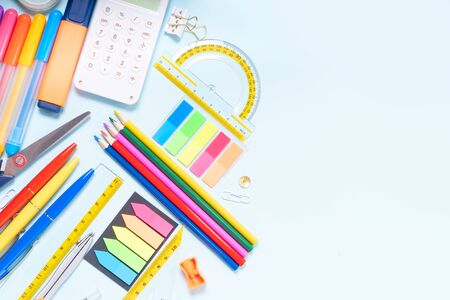 Back to school concept with colorful school supplies border on blue background with copy space