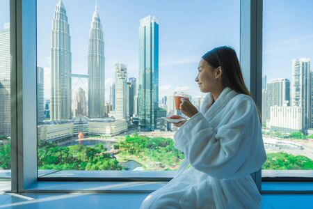 Young asian woman travel around kuala lumpur and enjoy coffee cup and looking the city in malaysia