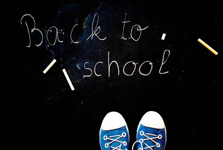 Chalk and kid s feet on black background wearing sneakers back to school concept Stock Photo