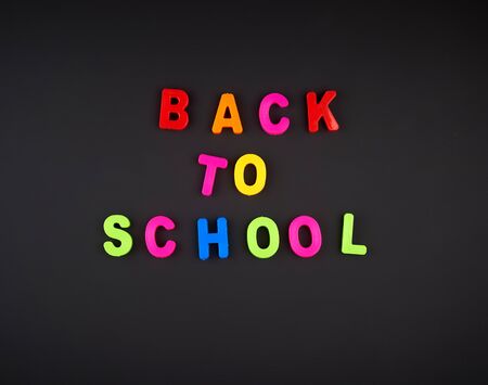 Inscription back to school from multi colored plastic letters on black chalk board concept back to school