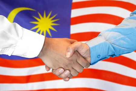 Business handshake on malaysia flag background men shaking hands and malaysia flag on background support concept