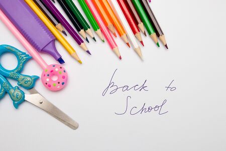 Colored pencils scissors pen marker on a white piece of paper copy space top view back to school Stock Photo