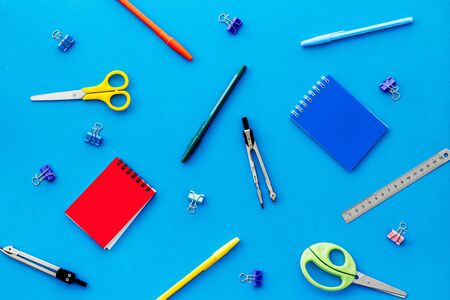 Flat lay stationery set notebook pen scissors on blue background top view