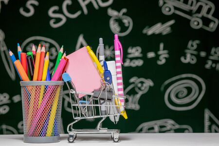 Back to school background with books pencils and globe on white table on a green blackboard background