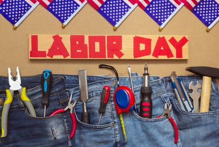 Jeans with tools on masonite plate with duct tape text and us flags top view patriotic holiday concept of labor day Stock Photo