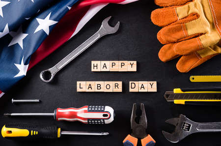 Happy labor day concept american flag with different construction tools on black table background with copy space for text