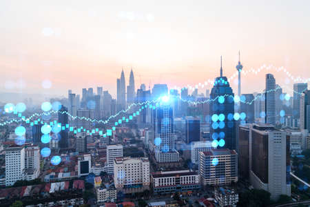 Glowing forex graph hologram aerial panoramic cityscape of kuala lumpur at sunset stock and bond trading in kl malaysia asia the concept of fund management double exposure