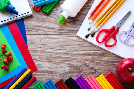 A set of stationery items on a wooden background colored paper plasticine and paints Stock Photo