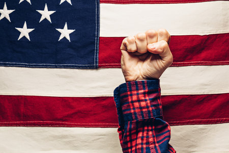 Hand clenched into fist against us flag strength power and reliability of usa and labor day concept