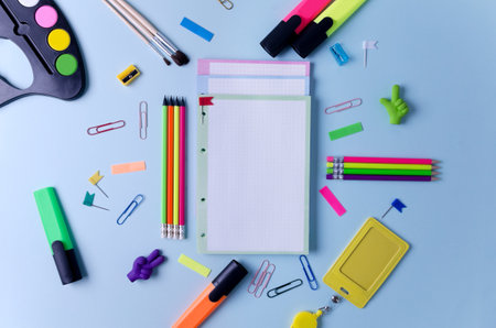 Notebooks pencils markers and other stationery lie on a blue background concept back to school goods for school office flat layout space copying selective focus