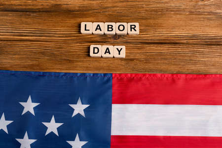 Top view of usa flag near cubes with labor day lettering on wooden table