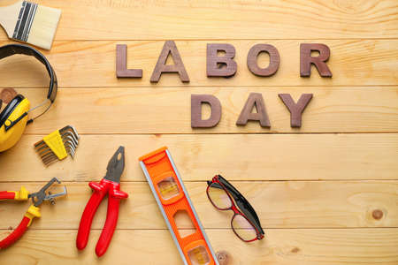 Set of tools and text labor day on wooden background