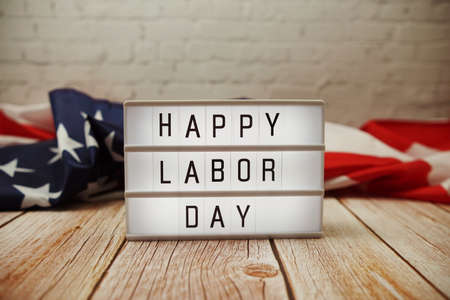 Happy labor day word in lightbox and american flag on wooden background Stock Photo