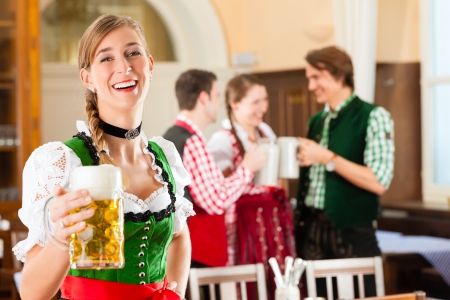 Young people in traditional bavarian tracht in restaurant or pub one woman is standing with beer stein in front the group in the background