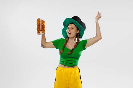 Happy excited woman in green yellow football kit holding beer mug and football ball supports favorite team soccer fans competition sport oktoberfest concept