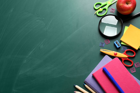 Flat lay composition with scissors and school supplies on chalkboard space for text