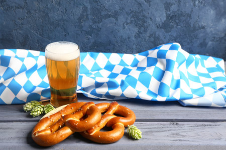 Flag of bavaria mug with beer and pretzels on blue wooden table