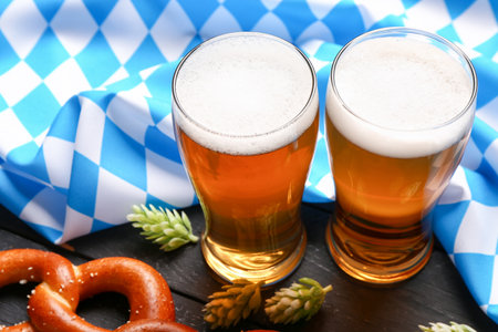 Flag of bavaria mugs with beer and pretzel on black wooden background closeup