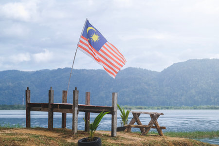 The malaysia flag is also known as jalur gemilang waves with a lake and hill in the background independence day or merdeka day celebration and hari malaysia copy space concept