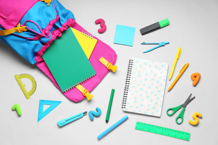 Composition with stylish school backpack and different stationery on gray background Stock Photo