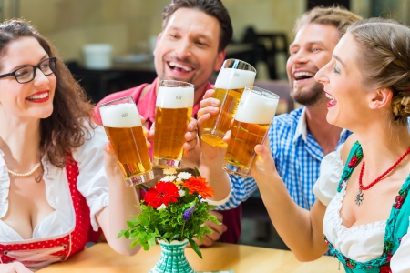 Friends in traditional bavarian tracht in restaurant or pub drinking beer in bavaria germany