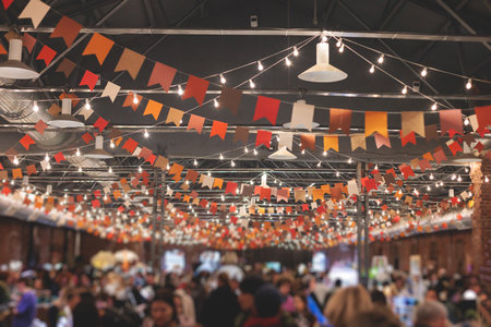 Crowded christmas market with new year decorations and multicolored flags balloons garlands and festoons indoor xmas fair interior retail kiosk and store with illumination and gifts for sale Stock Photo