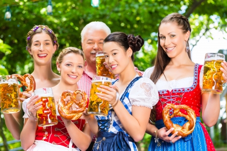 In beer garden friends man and women in tracht dirndl and lederhosen drinking a fresh beer in bavaria germany Stock Photo