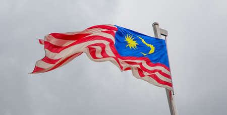 A malaysian flag over a stormy cloud sky Stock Photo