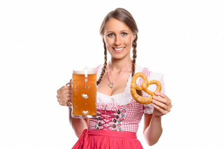 Smiling beautiful young woman with braided hair in a traditional red german or bavarian dirndl holding a glass tankard of beer and pretzel