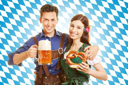 Happy couple at oktoberfest with beer and pretzel in front of bavarian flag Stock Photo