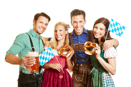 Group of happy friends celebrating oktoberfest with beer and pretzel in bavaria