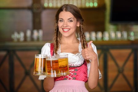 Beautiful waiter woman holding glasses of beer in a beer pub Stock Photo