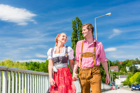 Couple visiting together bavarian fair in national costume leather pants and dirndl Stock Photo