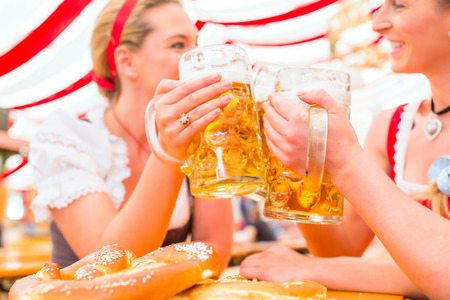 Friends drinking together bavarian beer in national costume or dirndl on oktoberfest Stock Photo