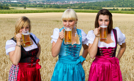 Three girls in dirndl drinking beer Stock Photo