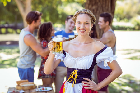 Pretty oktoberfest blonde toasting in the park on a sunny day