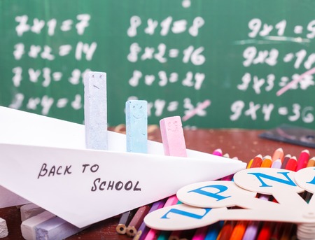 Colorful pencils of red yellow orange violet purple pink green and blue in stationary cup ruler fan english alphabet and paper plane with back to school text horizontal picture Stock Photo